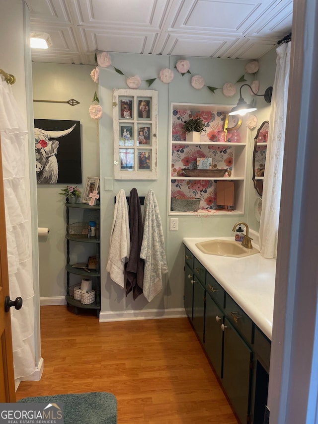 full bath with baseboards, wood finished floors, and vanity