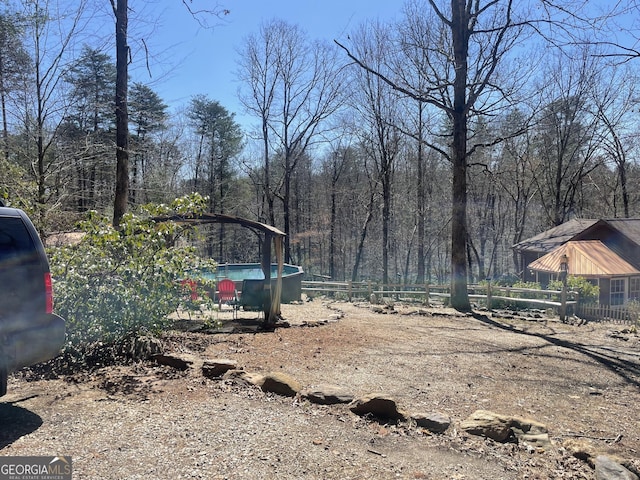 view of yard with a wooded view and fence