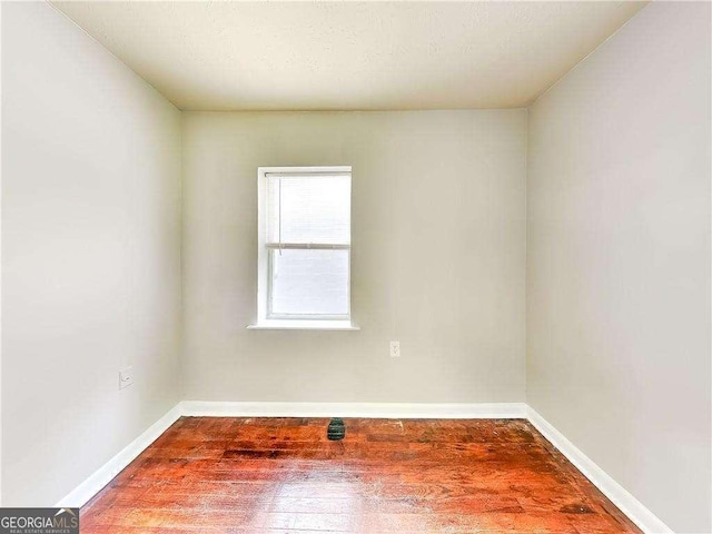 spare room featuring wood finished floors and baseboards