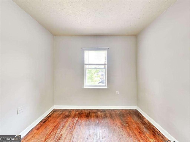 empty room featuring baseboards, a textured ceiling, and wood finished floors