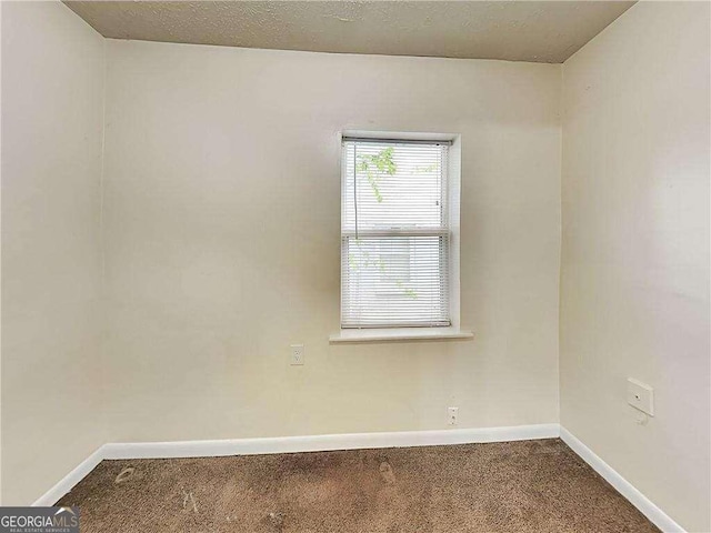 carpeted spare room featuring baseboards