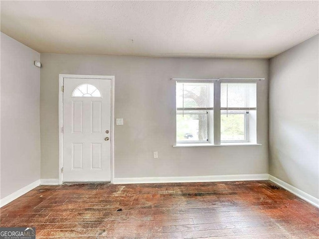 foyer entrance featuring a textured ceiling, baseboards, and hardwood / wood-style floors