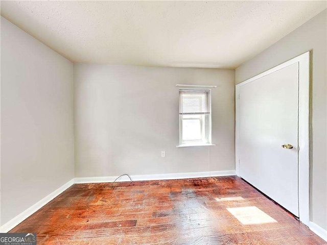 unfurnished bedroom with wood finished floors, baseboards, and a textured ceiling