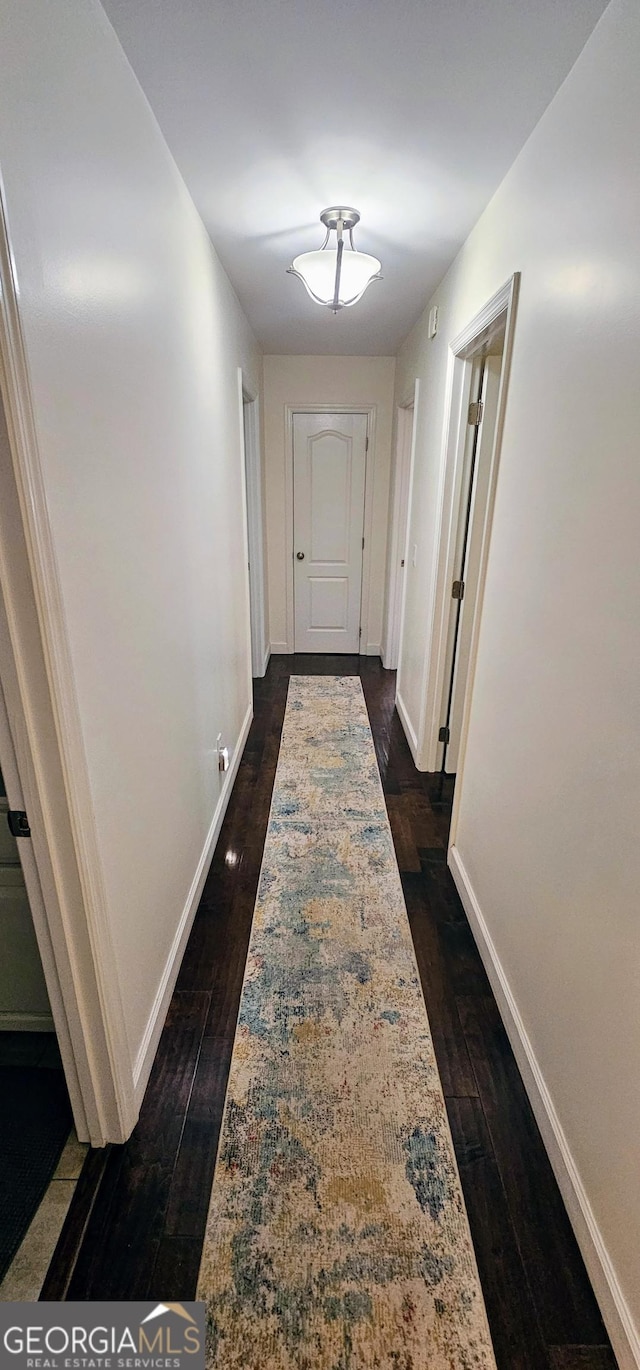 hall with dark wood finished floors and baseboards