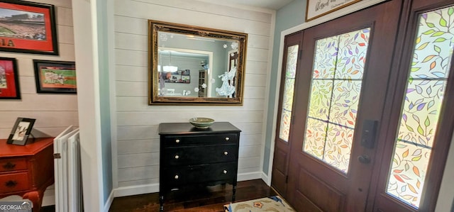 entrance foyer featuring baseboards and wood walls