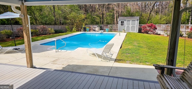 view of swimming pool featuring an outdoor structure, a fenced backyard, a lawn, and a shed