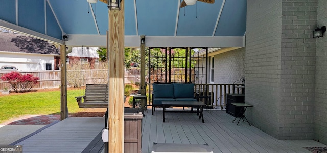 deck with outdoor lounge area, fence, and a lawn