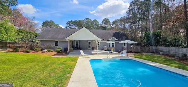 rear view of property with a patio area, a lawn, a fenced backyard, and a fenced in pool