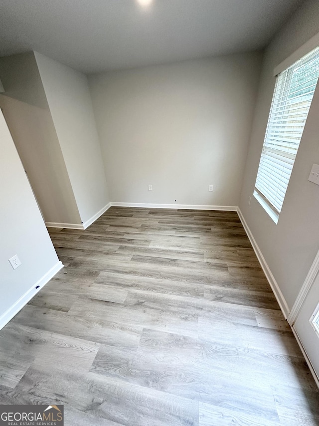 unfurnished room with baseboards and wood finished floors