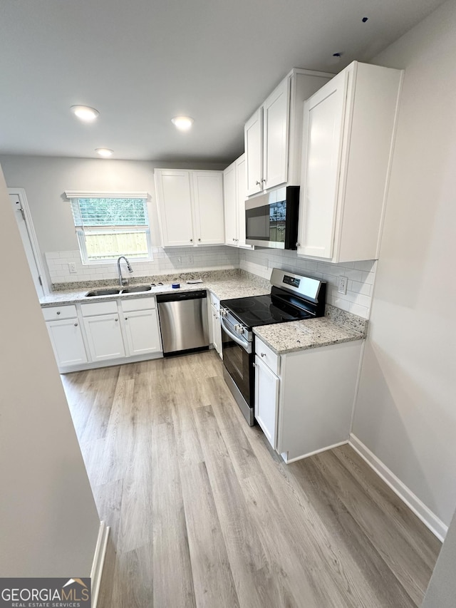 kitchen with decorative backsplash, white cabinets, appliances with stainless steel finishes, and a sink