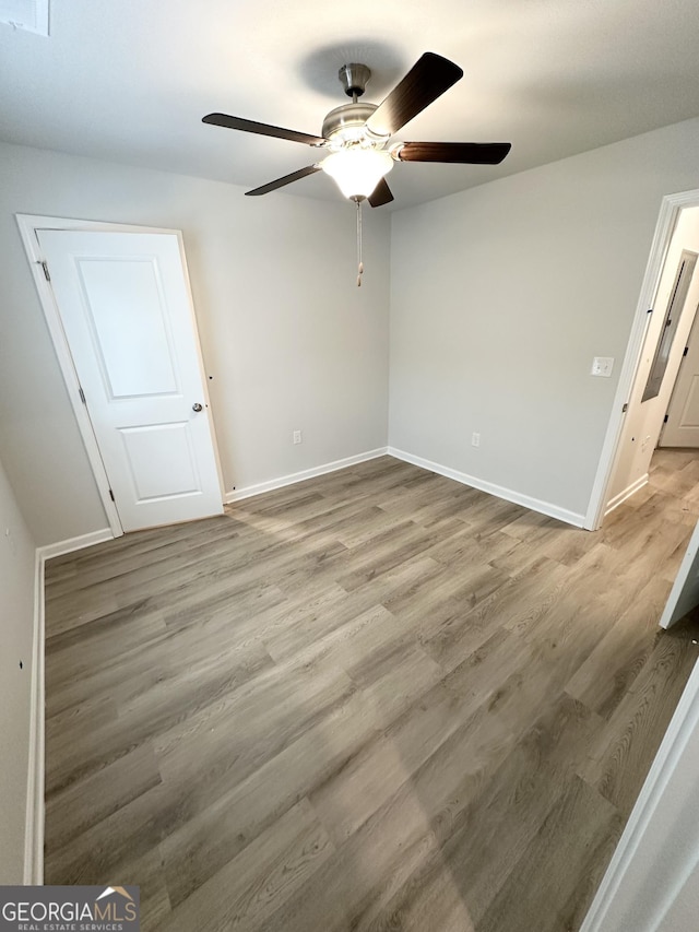 unfurnished bedroom featuring wood finished floors, baseboards, and ceiling fan