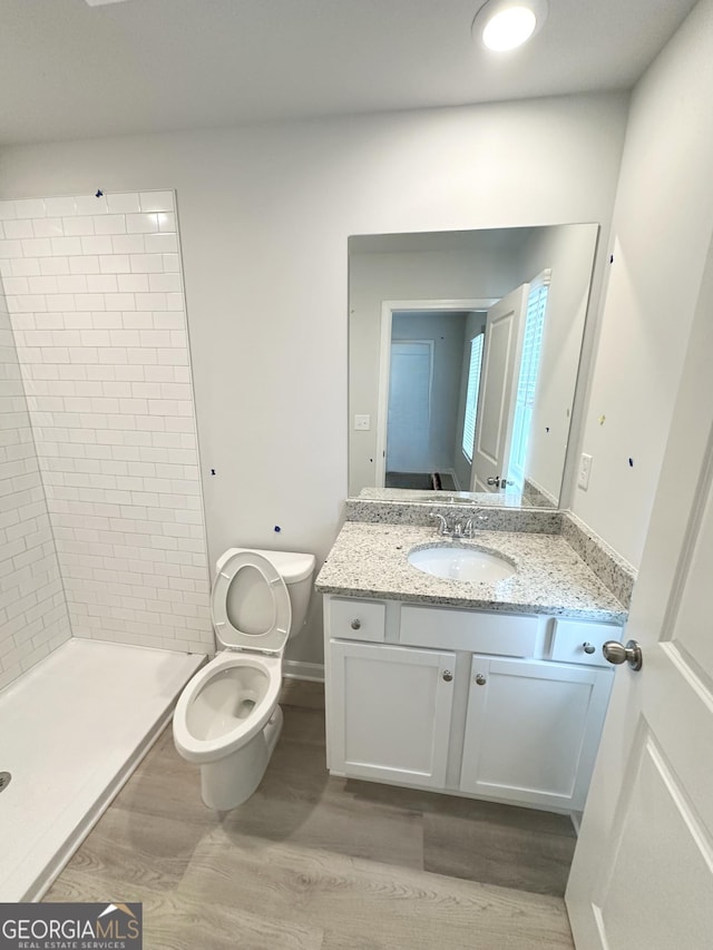 full bathroom featuring toilet, a stall shower, wood finished floors, baseboards, and vanity