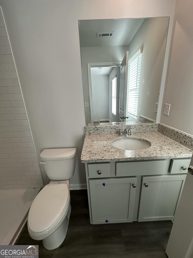 bathroom with visible vents, walk in shower, toilet, wood finished floors, and vanity