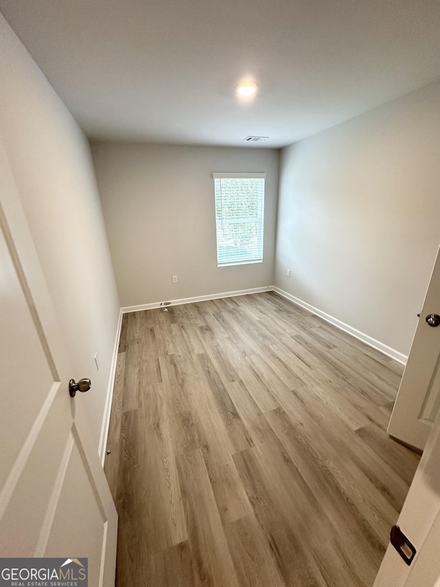 spare room featuring baseboards and wood finished floors