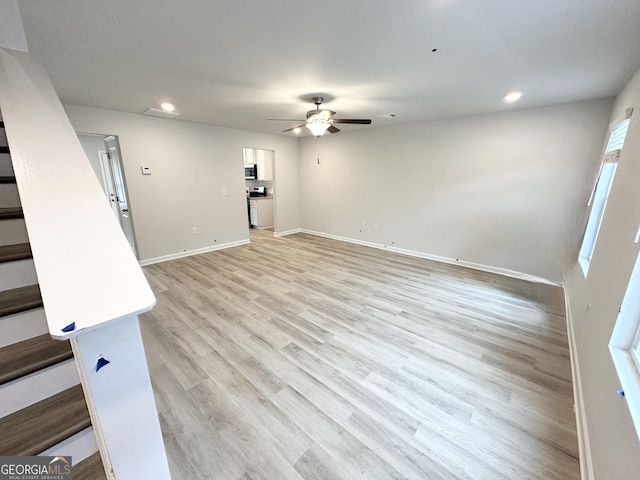 unfurnished living room featuring stairway, a ceiling fan, baseboards, recessed lighting, and light wood-style floors