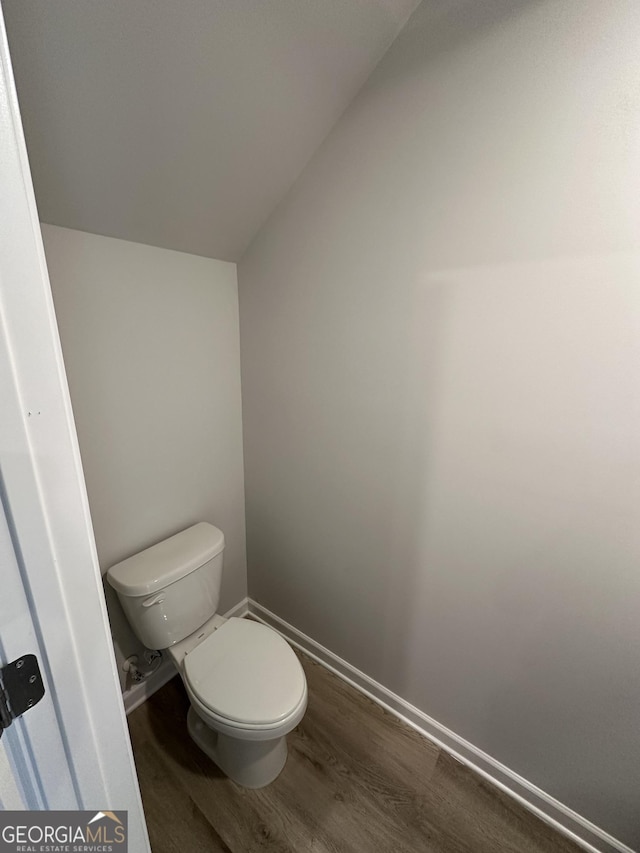 bathroom featuring vaulted ceiling, toilet, baseboards, and wood finished floors