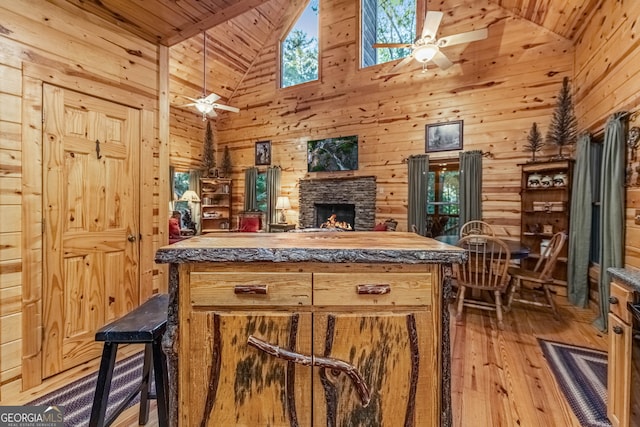 kitchen with a fireplace, ceiling fan, wooden ceiling, and wood walls