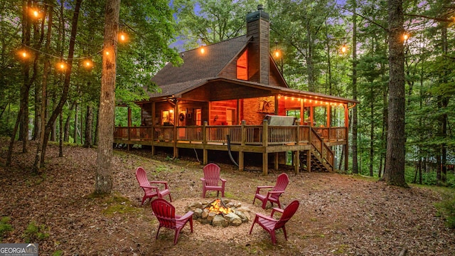 back of property featuring a chimney, an outdoor fire pit, stairs, and a deck