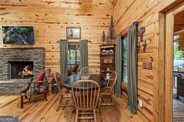 dining room featuring a fireplace, light wood-type flooring, and wood walls