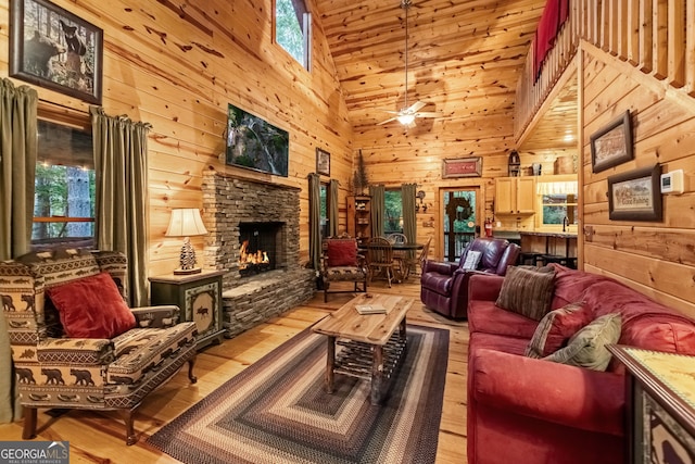 living area with light wood finished floors, ceiling fan, wood walls, wood ceiling, and a fireplace