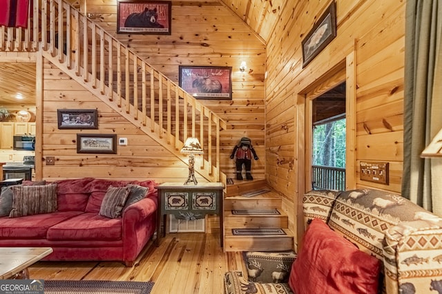 living area with wooden walls, high vaulted ceiling, and hardwood / wood-style flooring