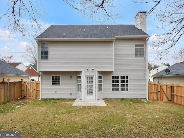 rear view of property with a gate, a patio area, a yard, and a chimney