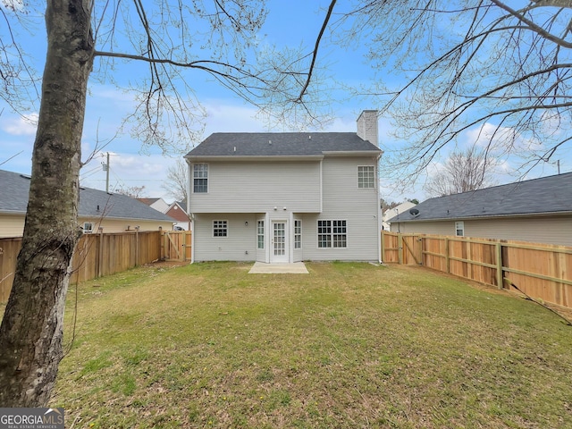 back of house featuring a lawn, a fenced backyard, and a chimney