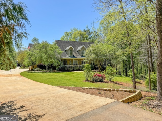 cape cod home featuring concrete driveway and a front lawn