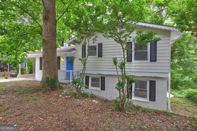 tri-level home with brick siding and a carport