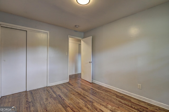 unfurnished bedroom featuring a closet, baseboards, and wood finished floors