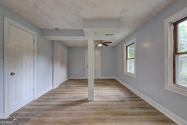 spare room featuring light wood-style flooring, a wealth of natural light, ceiling fan, and visible vents