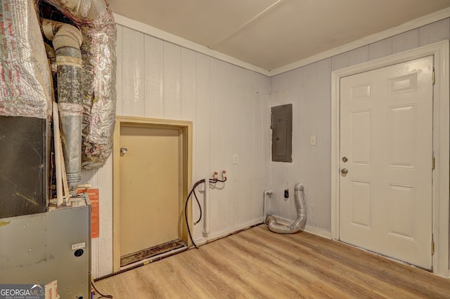 clothes washing area featuring wood finished floors, ornamental molding, laundry area, and electric panel
