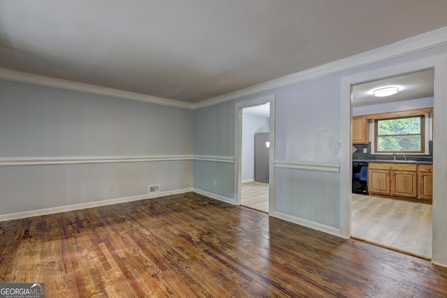 unfurnished living room with ornamental molding, baseboards, and wood finished floors