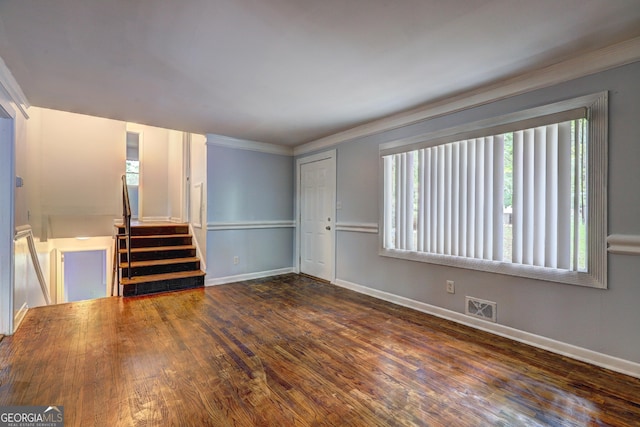 unfurnished living room with visible vents, crown molding, baseboards, wood finished floors, and stairway