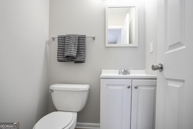 bathroom with toilet, vanity, and baseboards