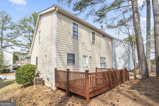 rear view of house featuring a wooden deck, central air condition unit, and a chimney