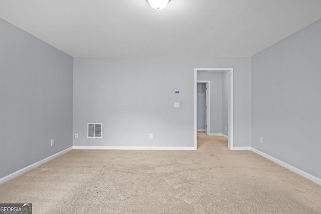 spare room featuring light carpet, visible vents, and baseboards