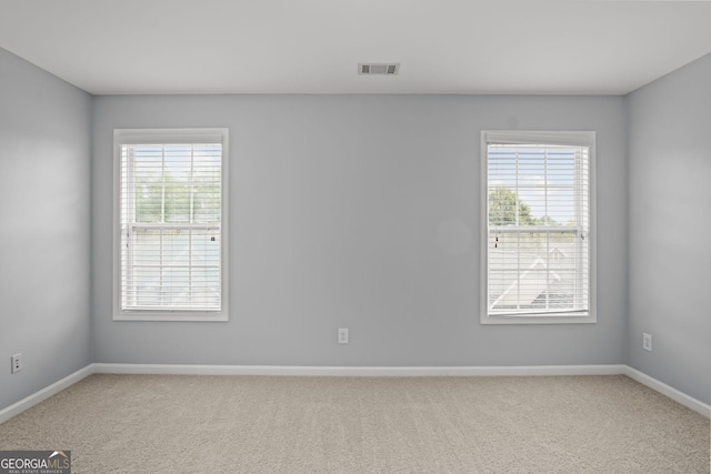 carpeted spare room featuring baseboards and visible vents