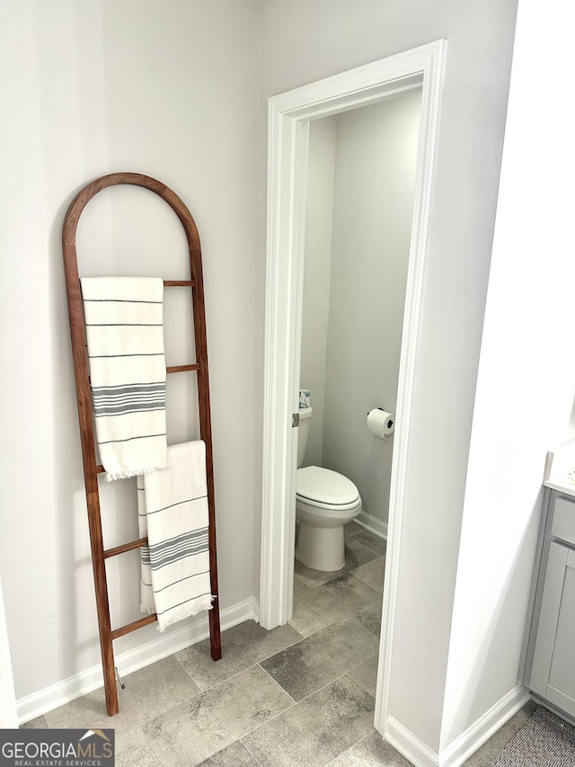 bathroom with vanity, toilet, and baseboards