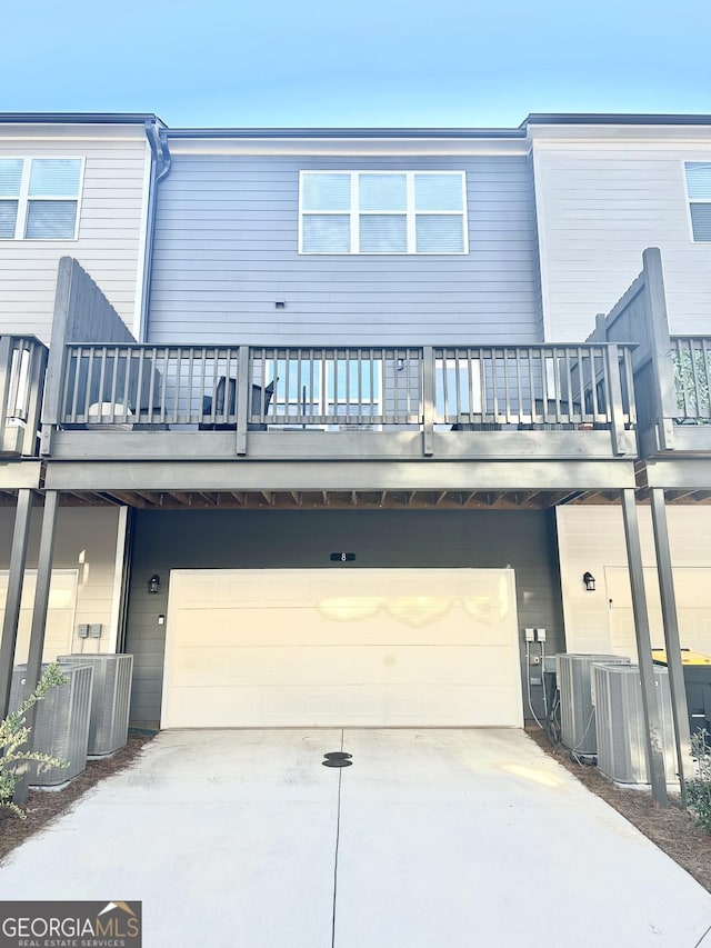 rear view of property featuring central AC unit, an attached garage, and concrete driveway