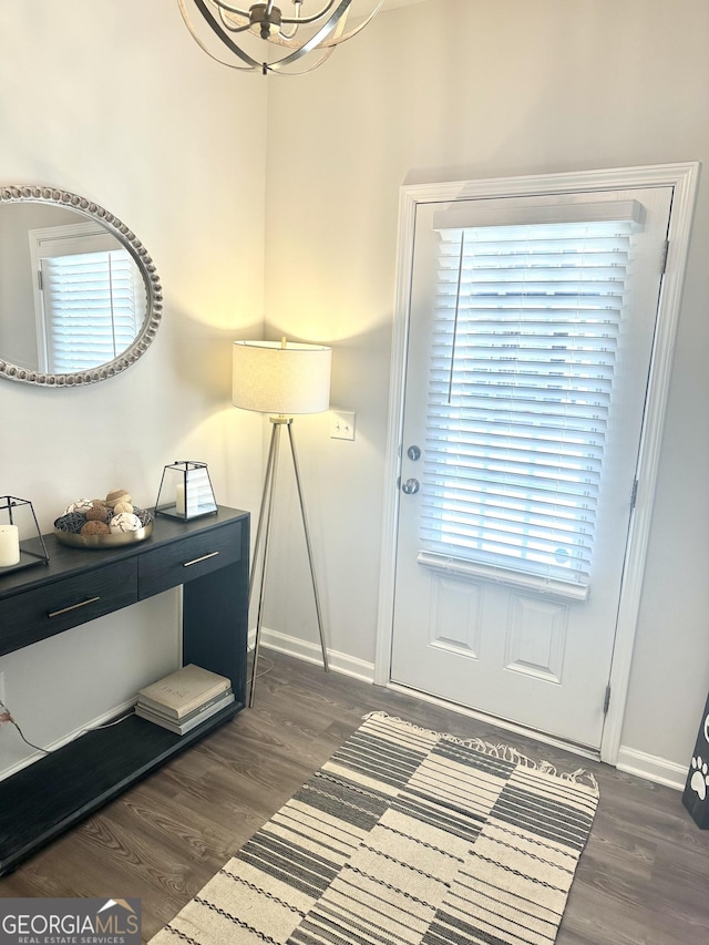 entryway featuring baseboards, a chandelier, and dark wood-style flooring