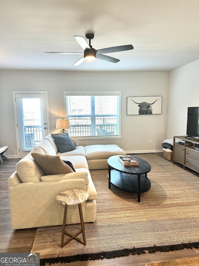 living room featuring baseboards, dark wood-type flooring, and a ceiling fan