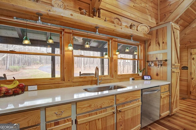 kitchen with wood walls, dishwasher, light countertops, and a sink