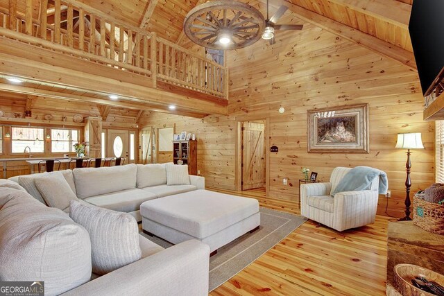 living room featuring wooden walls, beamed ceiling, ceiling fan, and wood finished floors