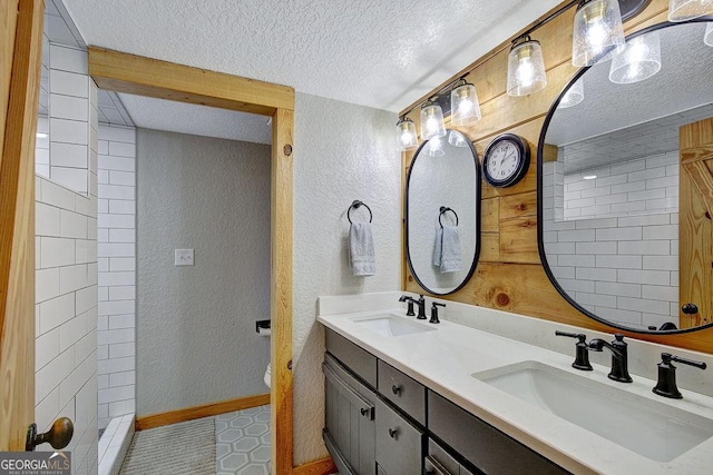 bathroom with a textured ceiling, a textured wall, and a sink