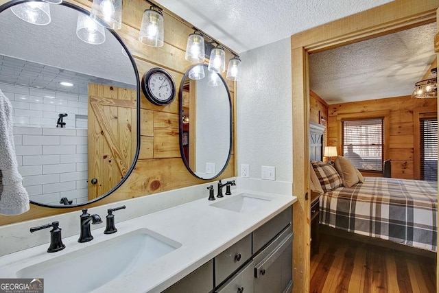 ensuite bathroom featuring a sink, connected bathroom, a textured ceiling, and wood finished floors