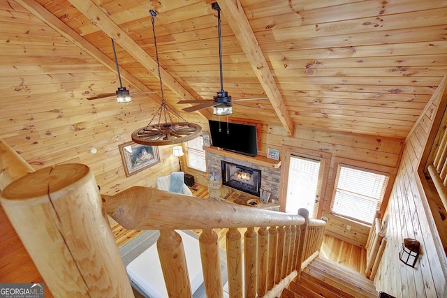 unfurnished living room featuring wooden walls, wood ceiling, ceiling fan, and a fireplace