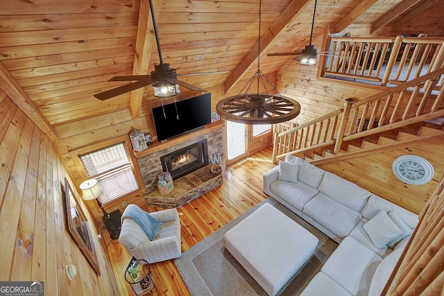 living room featuring hardwood / wood-style flooring, wooden walls, a ceiling fan, and wooden ceiling