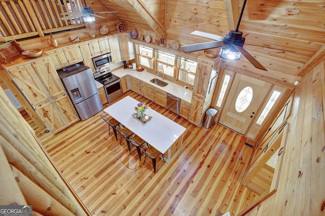 living room with a ceiling fan, lofted ceiling with beams, wood walls, wooden ceiling, and light wood-type flooring