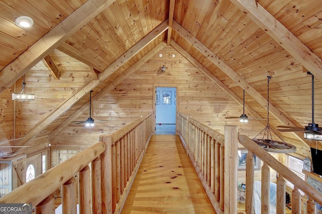 hall with wooden ceiling, light wood-style flooring, an upstairs landing, and wood walls